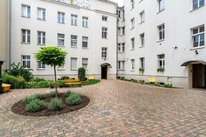A picturesque courtyard with cobblestone paths, green plants, and a well-maintained historic building exterior.

