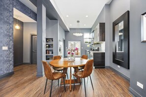 Wide view of the  kitchen with chairs on warm hardwood floors.