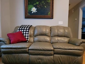 Comfortable leather sofa with reclining seats and footrests on each side.