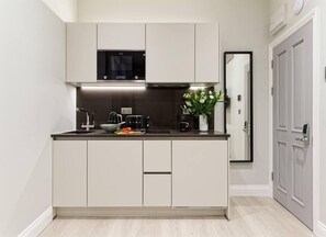 Open space with private kitchen area fully equipped with washing machine-dryer, oven-microwave, stove, kettle, toaster, Nespresso coffee machine, and kitchenware. Salt and pepper included. Non-included oils or food.