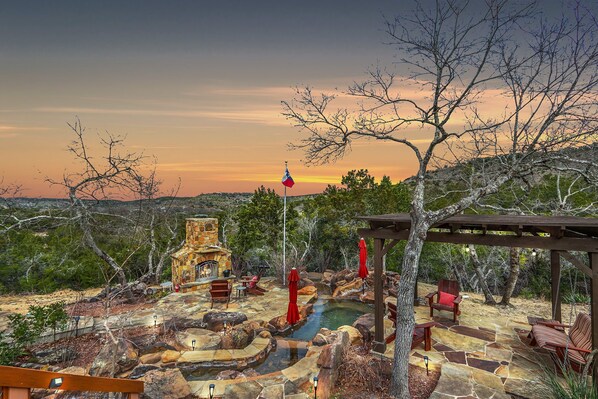 Backyard oasis with waterfall pool, covered seating, and outdoor fire place!