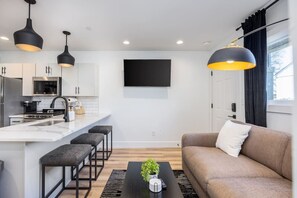 Cozy living room off the kitchen with a Smart TV, pull-out couch, and room-darkening shades. Tasteful decor & details provided for your comfort throughout the condo.