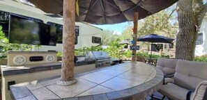 Huge tiki area with big screen tv and gas grill with fridge