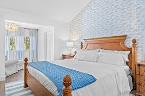 Primary bedroom with king bed, vaulted ceilings, smart TV, private attached bathroom and additional seating area