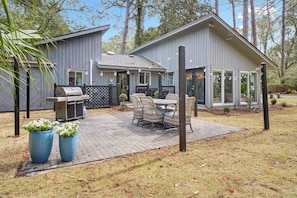 Backyard with ample grass, grill, table and string lights