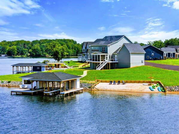 Lakefront home with a private dock, sandy beach area, and stunning water views.