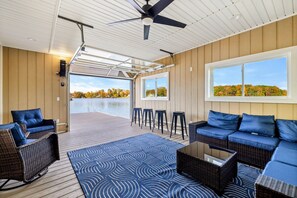 A stylish indoor-outdoor lakefront space with plush seating, a bar area, and a retractable door for seamless access to the water