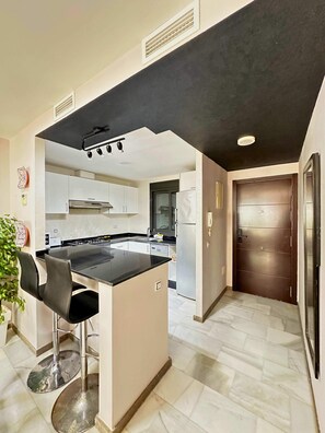 Entrance to the apartment with open kitchen and high table for breakfast