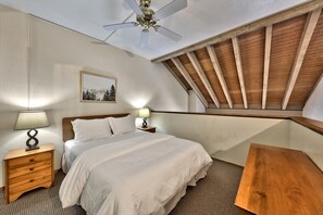 King bed in the loft with nightstand and ceiling fan