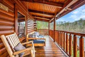 The porch includes an oversized porch swing, rocking chair, bench, and the hot tub.