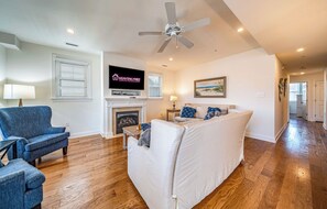Bright coastal living room with fireplace and TV