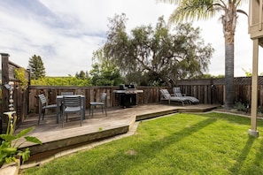Backyard deck BBQ and sunning chairs. Also a small grass area.