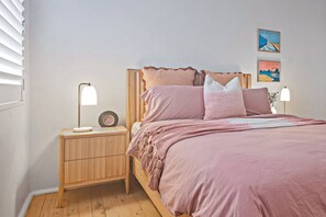 The beautifully appointed first bedroom features a queen-size bed, with side tables and reading lamps.
