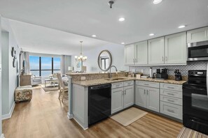 Modern and spacious kitchen equipped with appliances and a granite-top peninsula, perfect for preparing meals with an ocean backdrop.