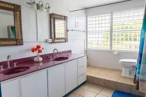 Spacious bathroom with 2 sinks, shower, windows and essentials. 