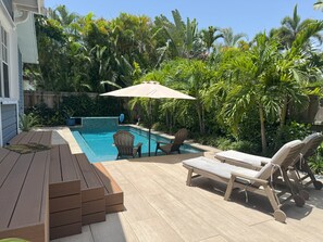 Beautifully landscaped backyard features waterwall pool with in-pool umbrella