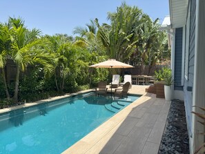 Beautifully landscaped backyard features waterwall pool with in-pool umbrella