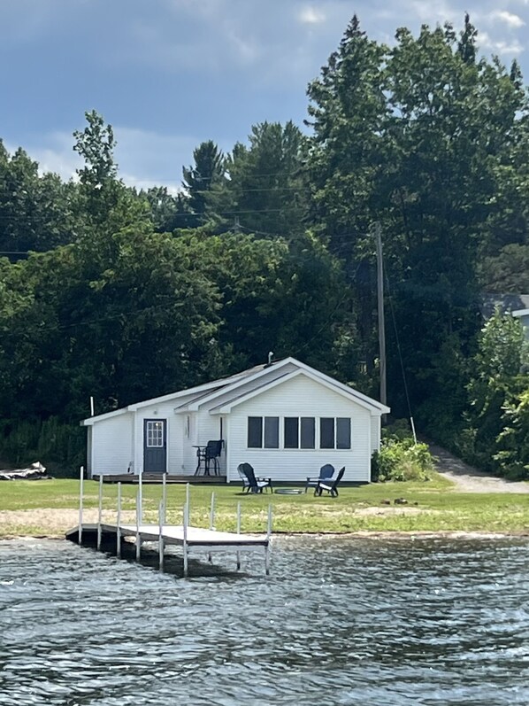 View of the house from water including the shared dock and fire pit.