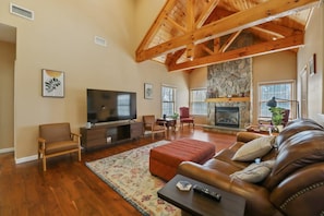 Family room with natural wooden beam cathedral ceiling, and fireplace.