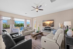 Step into luxury in this expansive family room, where plush reclining sofas beckon, inviting you to sink into comfort. The focal point is a fireplace alive with a spectrum of colors, casting a warm and inviting glow.