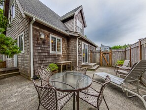 Fully fenced back yard with outdoor dining seating and lounge chairs