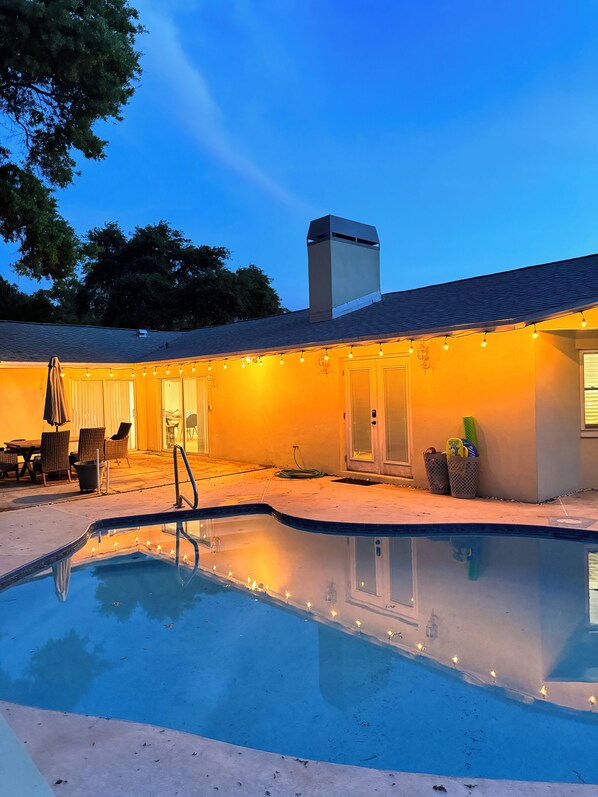 Backyard pool at night with outdoor dining