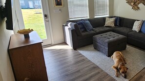 Family Room with large sectional & ottoman.
65" Smart TV, Open concept for families.