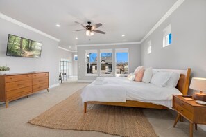 This is the primary bedroom with a King size bed, Smart TV, an attached bathroom, a desk space, and a private balcony with seating.