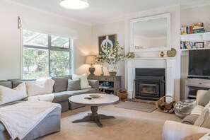 An elegant living area features a cosy fireplace along with two sofas and a chaise.
