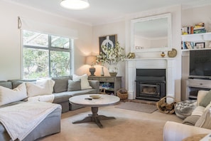 An elegant living area features a cosy fireplace along with two sofas and a chaise.