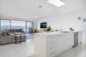 The sleek kitchen is designed around a central island and is fit with high-quality appliances and cooking utensils.
