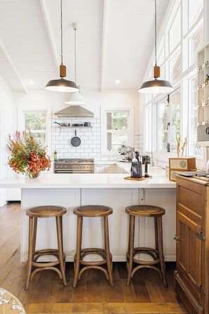 The timeless kitchen features wooden cabinetry, a tiled splashback and U-shaped counter with benchtop seating to snack before hitting the wineries.
