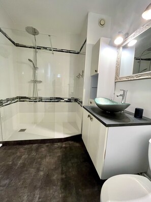 Salle d'eau avec douche à l'italienne, lavabo, wc et rangements à disposition
