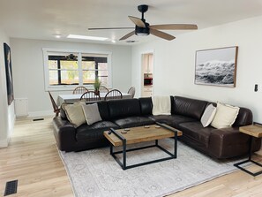 Open family room with sectional couch and large smart tv overlooking backyard. 