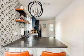 Kitchen has counter with 2 stools. 