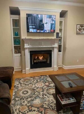 Living room with comfortable sofa, 55" flat screen (Netflix) and fire place.