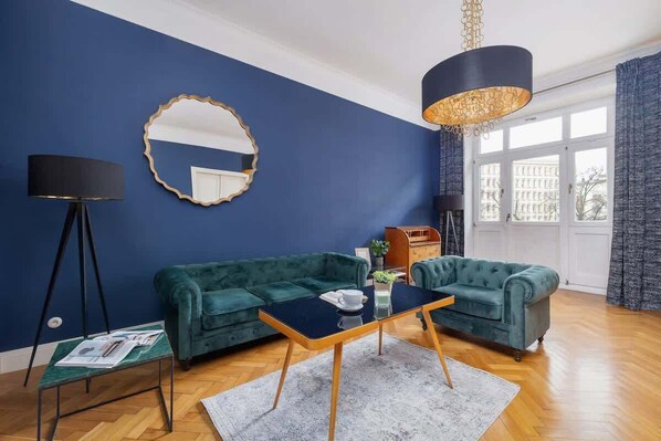 Spacious and bright, with large windows, elegant blue walls, and stylish furniture.