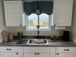 Kitchen with coffee station, oven/stove, microwave, fridge, cooking utensils