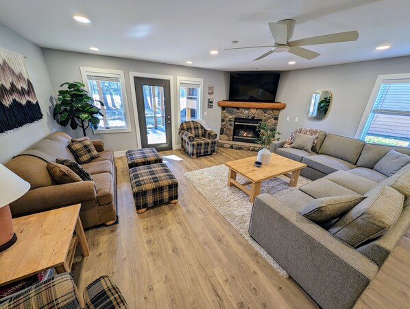 Large, bright main room with plenty of seating, cozy fireplace, and 65" TV. 