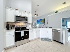 - Fully equipped kitchen featuring stainless steel appliances and crisp white cabinets
- Hexagonal backsplash and beachy accents add a touch of playful elegance
- Open concept layout makes it easy to cook and stay connected with the group