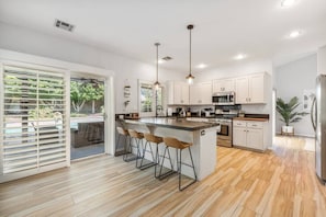 Modern kitchen with new appliances, large counter tops, and bar area. Fully stocked kitchen.