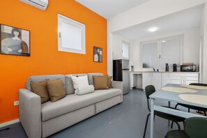 Modern living room featuring a stylish couch, coffee table, chairs, and a mounted flat-screen TV.