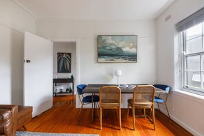 Enjoy dining on the large wooden table that comfortably seats four guests. The dining chairs are an interesting combination of a blue velvet upholstered pair and a rattan chair set. 
