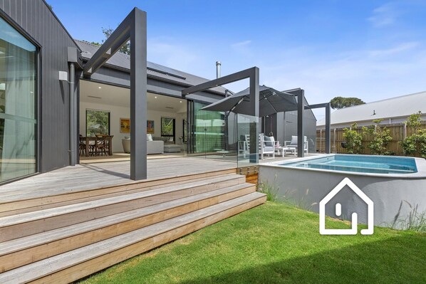 Outdoor lounge with large cantilever umbrella and Weber BBQ