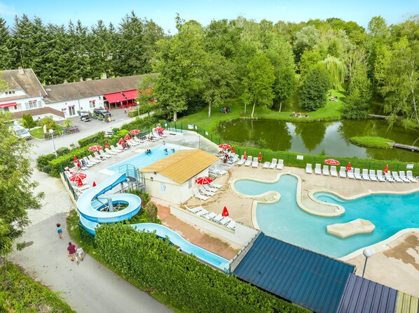 A vibrant water park nestled in greenery, perfect for a day of fun and relaxation, with plenty of space to soak up the sun.