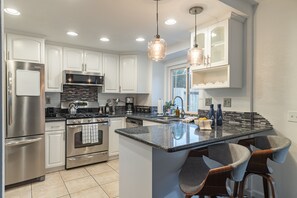 Kitchen is fully equipped and features stainless steel appliances and barstool seating.