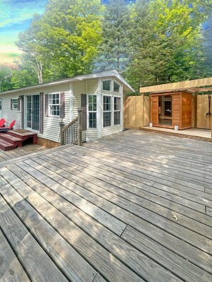 L-shaped deck wraps around tiny home, includes sauna and outdoor shower!