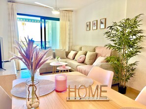Living room with sea views, large sofa, and dining table. Perfect for relaxing and enjoying your vacation.