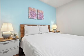 Inviting, pristine queen bed with charming coastal decor for restful nights.