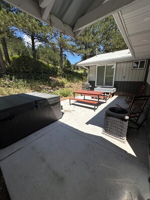 Back patio with grill, picnic table and hot tub.